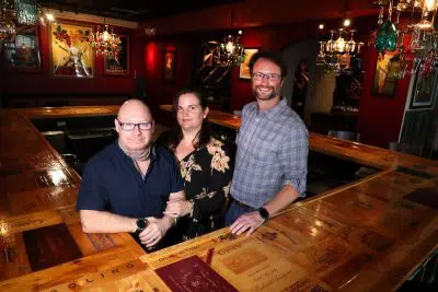 'Co-owners Clayton Chelley, wife Valerie Chelley and David Bell at the iconic bartop in Vinos Wine Bar and Cocktail Lounge